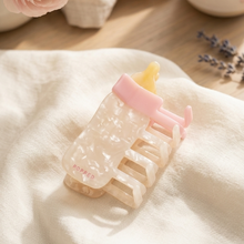 Load image into Gallery viewer, Pink and White Hair Clip with yellow nipple lays on white linen cloth with lavender, pink flowers and other misc. items on the table
