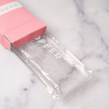 Load image into Gallery viewer, The Popped hot and cold packs are lying flat on the counter and coming halfway out of the packaging.
