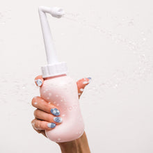 Load image into Gallery viewer, Woman holds the Popped peri bottle upright and squeezes it to spray water
